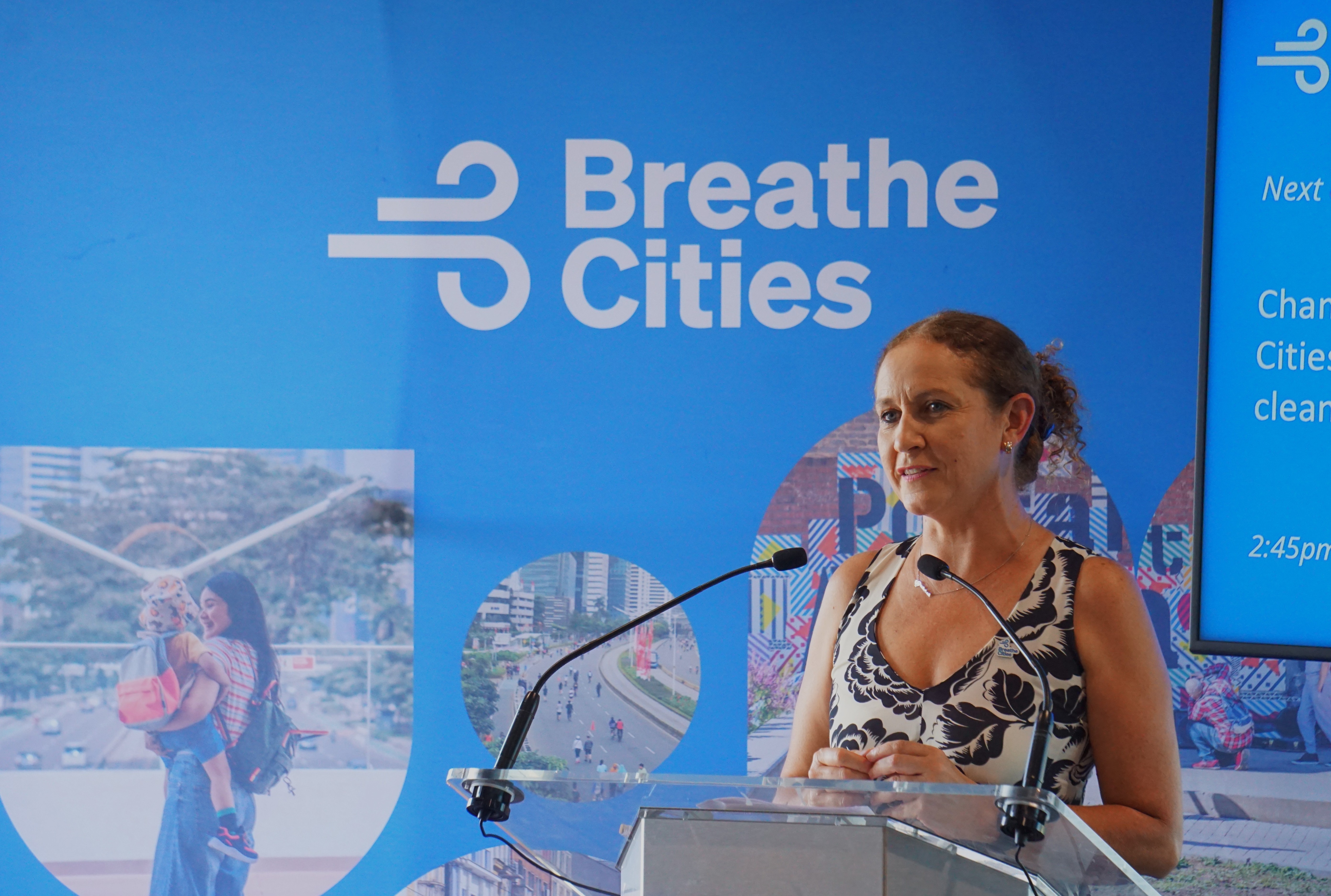 Cecilia Vaca Jones, Executive Director of Breathe Cities, speaking at a podium in front of a Breathe Cities backdrop.