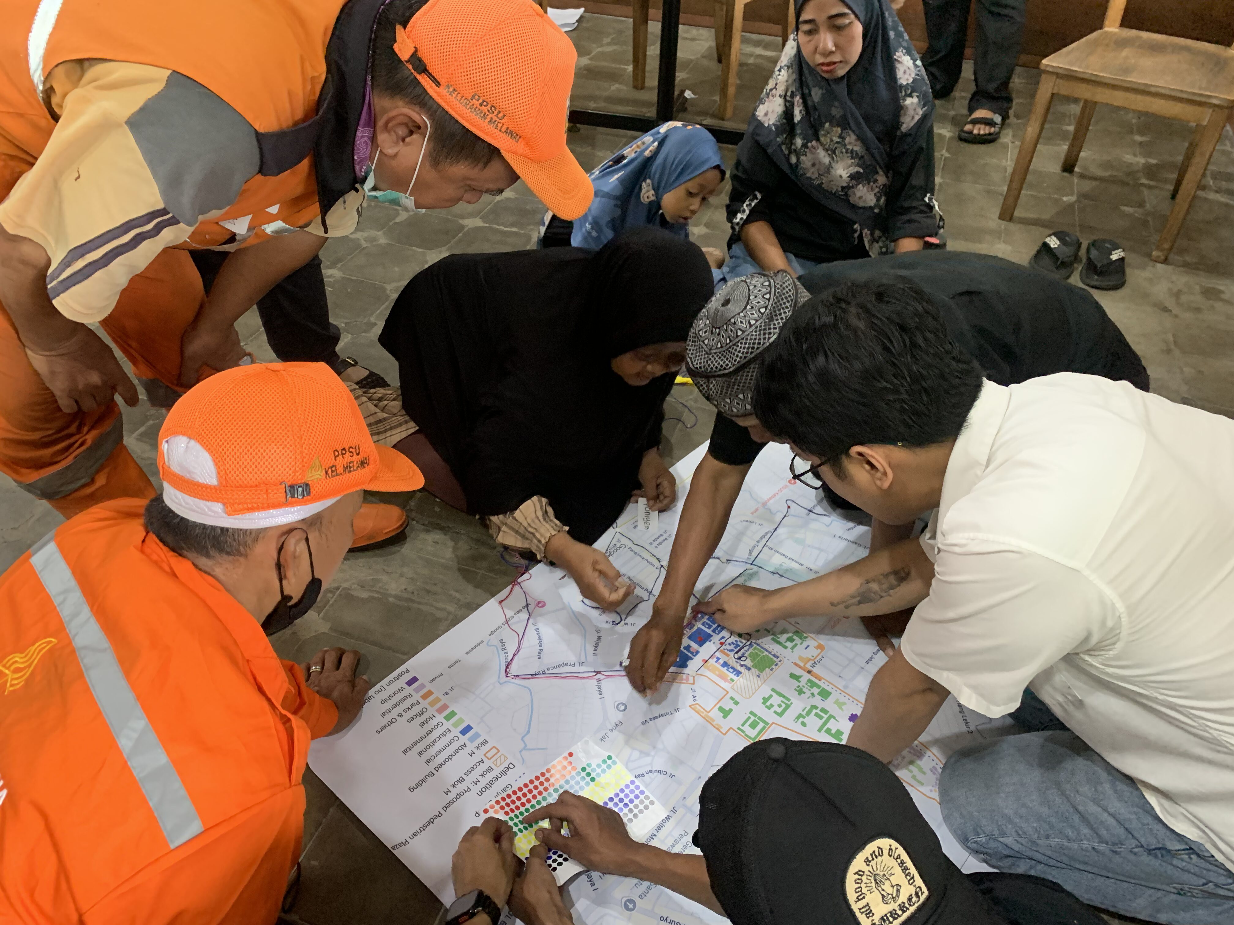 Community members and Kelurahan Melawai PPSU municipal workers examining a map during a Blok M focus group discussion for Jakarta’s Low Emission Zone (LEZ).