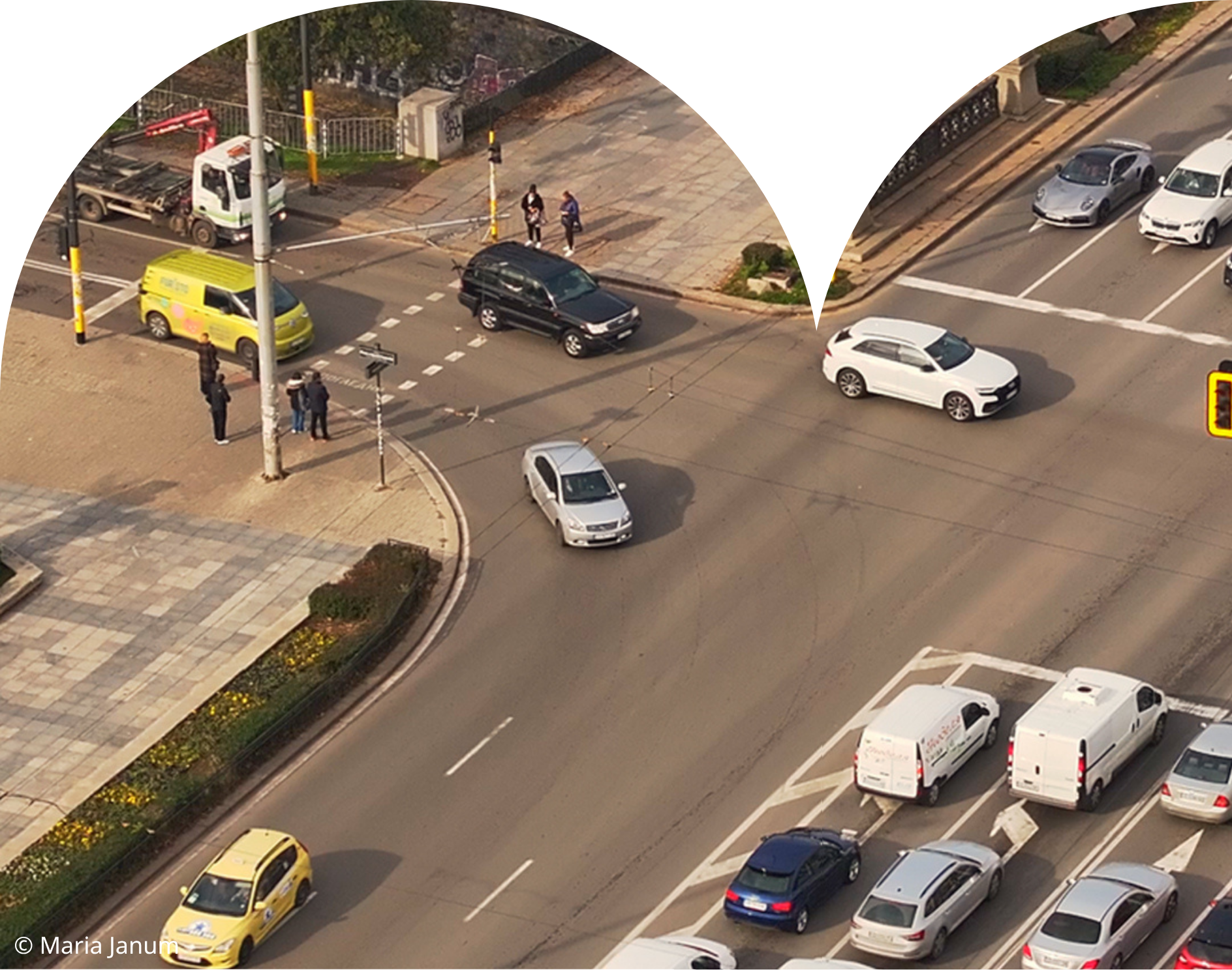 High-angle aerial view of cars, taxis, and pedestrians navigating a busy street intersection in Sofia, Bulgaria.