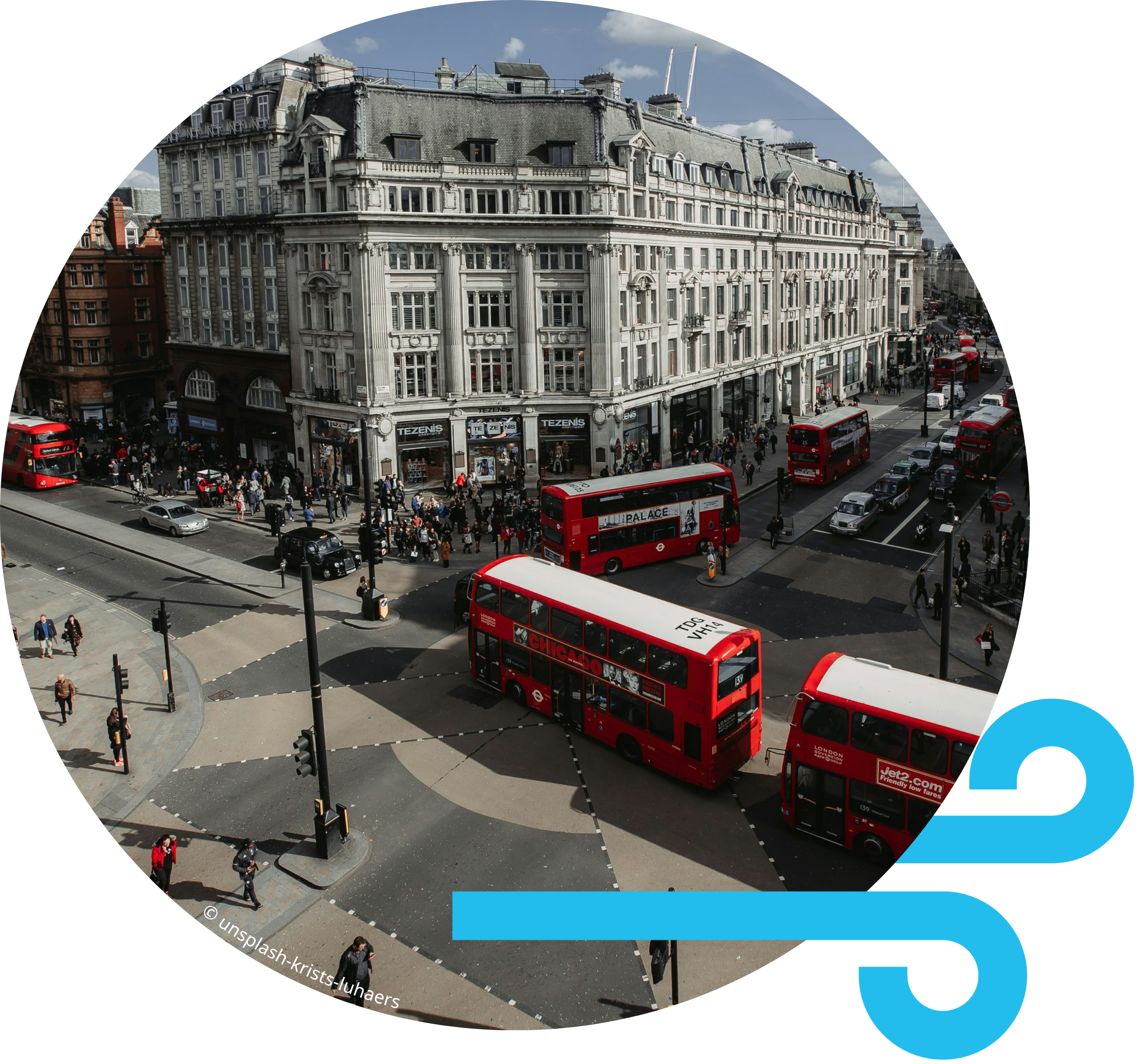 Red double-decker buses driving through a London Clean Air Zone street.